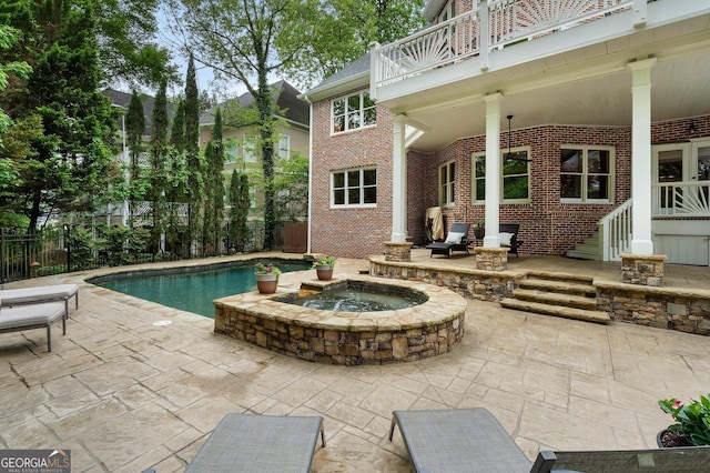 view of swimming pool with an in-ground hot tub, a patio, and fence