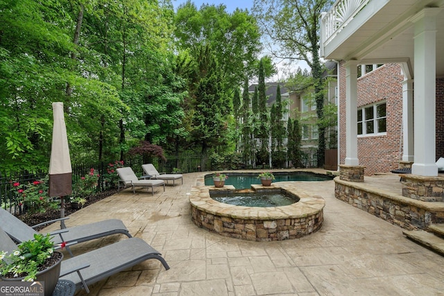 view of patio / terrace with an outdoor hot tub and fence