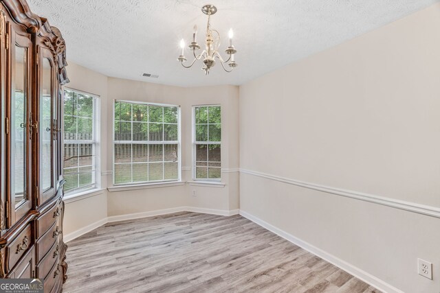 675 Michael Cir, Monroe, GA 30655 - spare room with a chandelier, light wood-type flooring, baseboards, and a textured ceiling