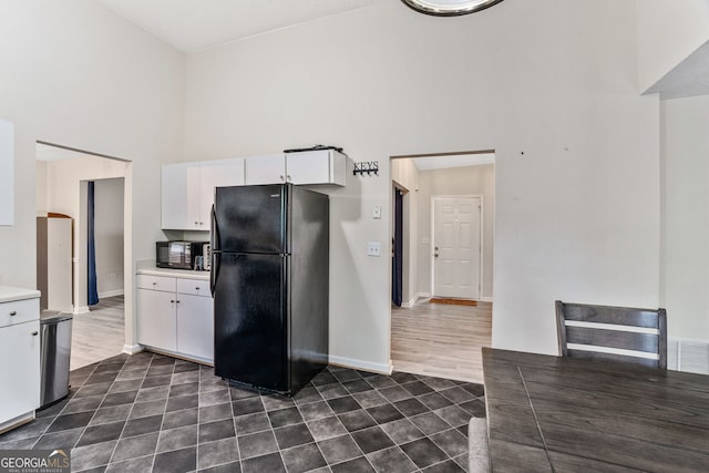 675 Michael Cir, Monroe, GA 30655 - kitchen featuring black appliances, a high ceiling, light countertops, white cabinets, and dark tile patterned floors