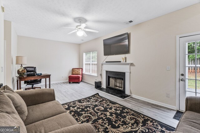 675 Michael Cir, Monroe, GA 30655 - living room featuring wood finished floors, ceiling fan, baseboards, a fireplace, and a textured ceiling