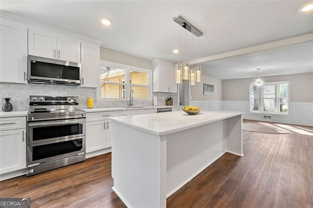 2490 Turtle Ter, Grayson, GA 30017 - kitchen with wainscoting, appliances with stainless steel finishes, a chandelier, and white cabinetry