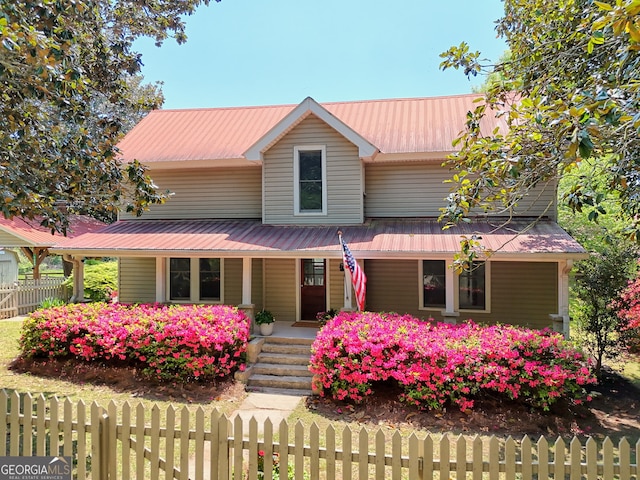 view of front of home featuring covered porch, a fenced front yard, and metal roof