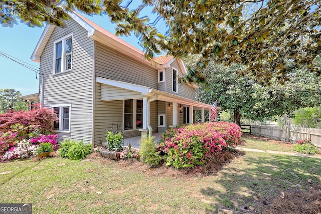 view of side of home with a lawn, a patio, and fence