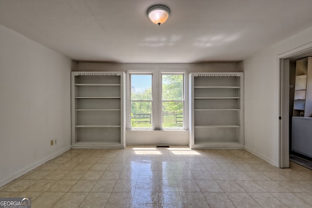 spare room featuring baseboards, light tile patterned flooring, and visible vents