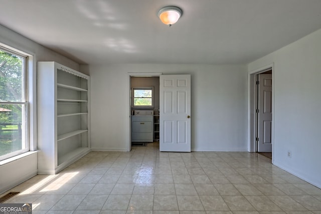 empty room with light tile patterned floors, baseboards, washer / clothes dryer, and visible vents