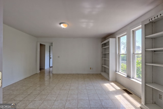 empty room with baseboards, light tile patterned flooring, and visible vents
