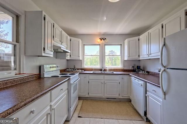 kitchen with dark countertops, white appliances, under cabinet range hood, white cabinets, and a sink