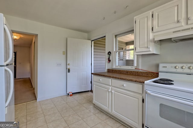 kitchen featuring dark countertops, under cabinet range hood, white cabinets, and white appliances