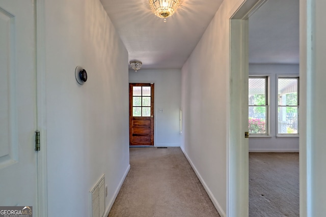 corridor featuring carpet floors, baseboards, and visible vents