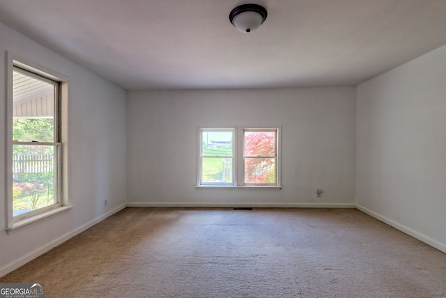 empty room featuring a healthy amount of sunlight, baseboards, and carpet flooring
