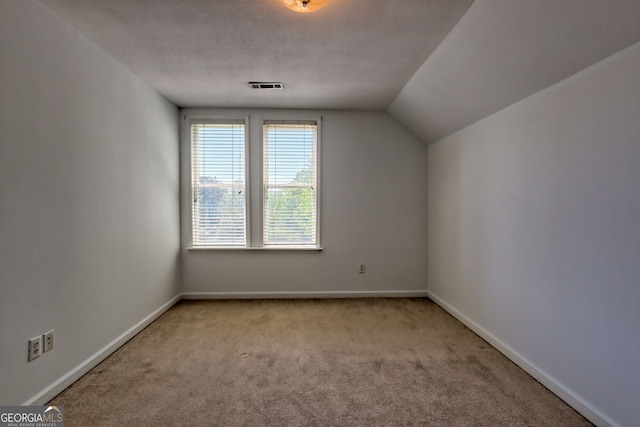 additional living space with vaulted ceiling, visible vents, baseboards, and carpet