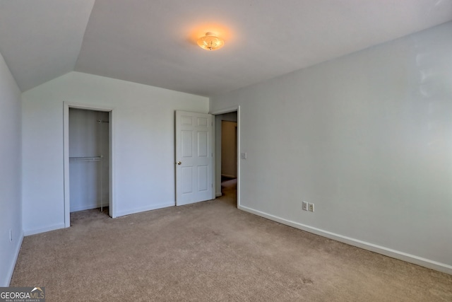unfurnished bedroom featuring baseboards, lofted ceiling, carpet, and a closet