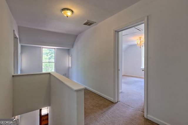 hallway with visible vents, vaulted ceiling, baseboards, an inviting chandelier, and carpet flooring