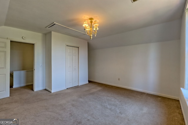 unfurnished bedroom with a closet, attic access, carpet, and baseboards