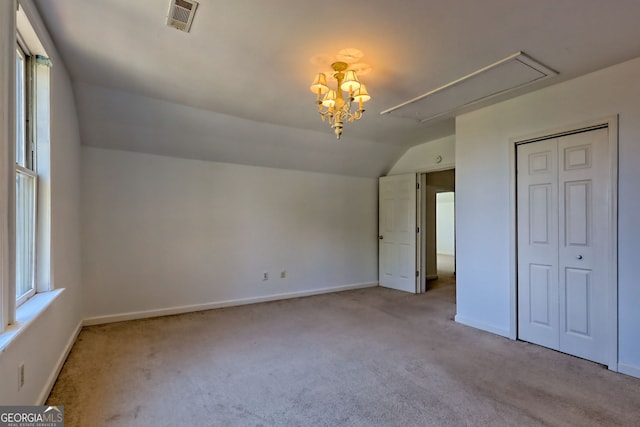 unfurnished bedroom with visible vents, carpet floors, baseboards, attic access, and vaulted ceiling