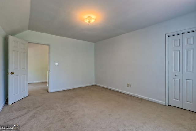 unfurnished bedroom with carpet floors, baseboards, and lofted ceiling