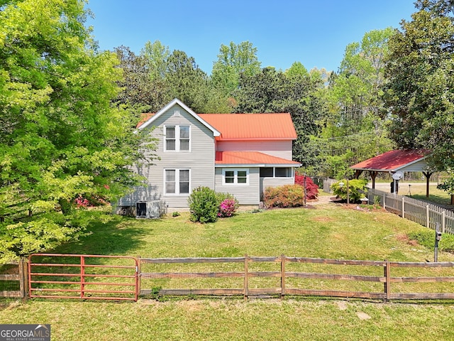 rear view of house featuring a lawn, a fenced backyard, and metal roof
