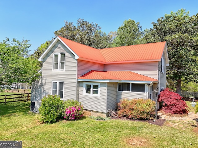 back of house with a yard, fence, metal roof, and central air condition unit
