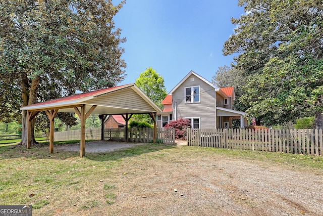 exterior space featuring a lawn, dirt driveway, fence, and a carport
