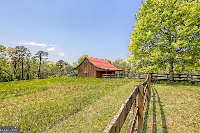 view of yard featuring a barn, an outdoor structure, and fence