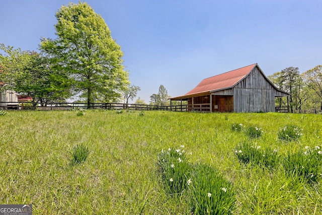 view of yard featuring an outdoor structure, a barn, and fence