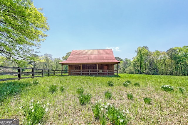 exterior space featuring fence, metal roof, and an outdoor structure