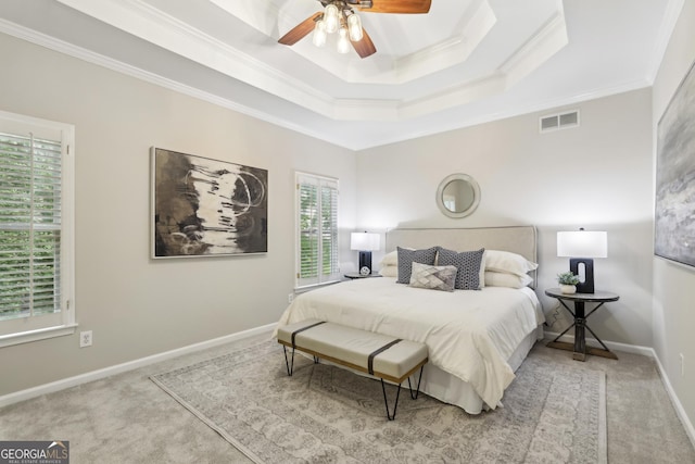 carpeted bedroom with ceiling fan, visible vents, crown molding, a raised ceiling, and baseboards