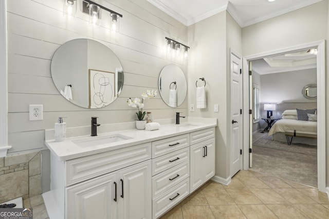 ensuite bathroom featuring a sink, crown molding, and double vanity