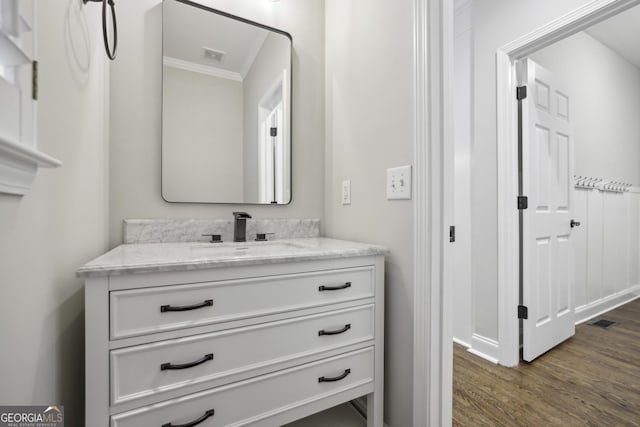 bathroom featuring crown molding, vanity, baseboards, wood finished floors, and visible vents