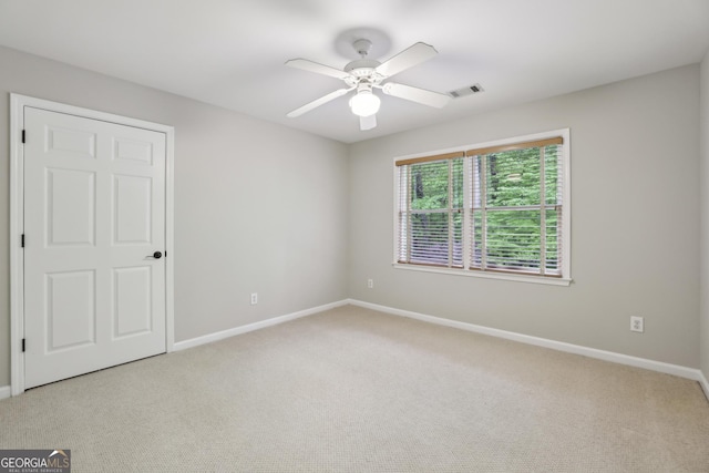 unfurnished bedroom featuring a ceiling fan, baseboards, light colored carpet, and visible vents