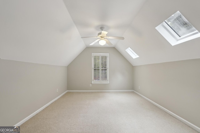 bonus room featuring carpet flooring, a ceiling fan, baseboards, and lofted ceiling with skylight