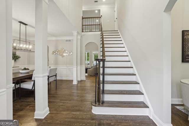 stairway with visible vents, ornamental molding, a high ceiling, and wood finished floors