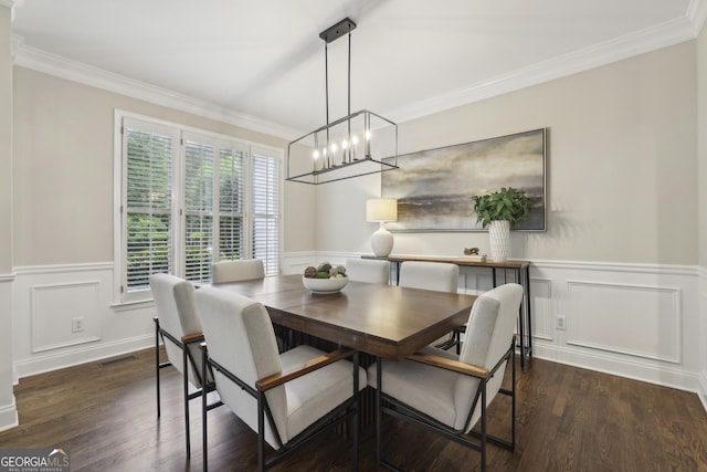 dining space featuring an inviting chandelier, wainscoting, a decorative wall, wood finished floors, and ornamental molding