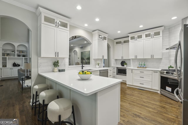 kitchen featuring ornamental molding, recessed lighting, arched walkways, a sink, and stainless steel appliances