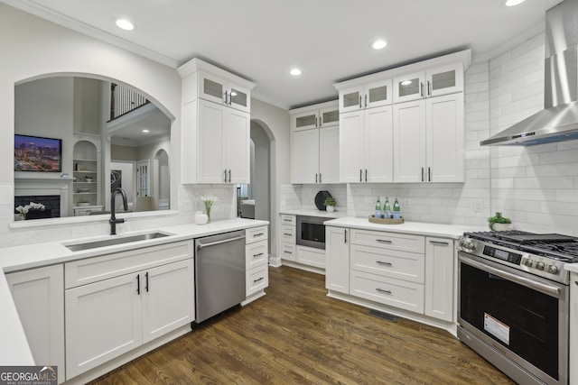 kitchen with recessed lighting, a sink, wall chimney exhaust hood, and stainless steel appliances