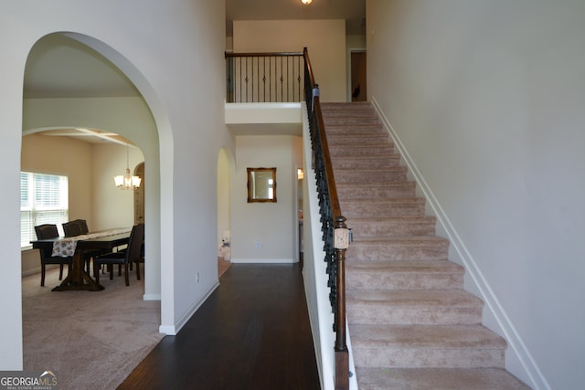 6816 Diamond Dr, Rex, GA 30273 - staircase with arched walkways, wood finished floors, baseboards, and a chandelier