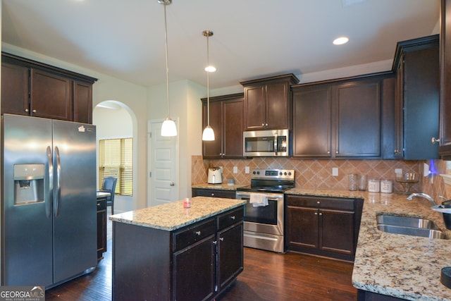 6816 Diamond Dr, Rex, GA 30273 - kitchen with stainless steel appliances, a sink, arched walkways, dark wood finished floors, and light stone counters