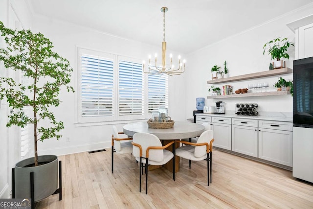 dining room featuring a chandelier, light wood-style floors, crown molding, and baseboards