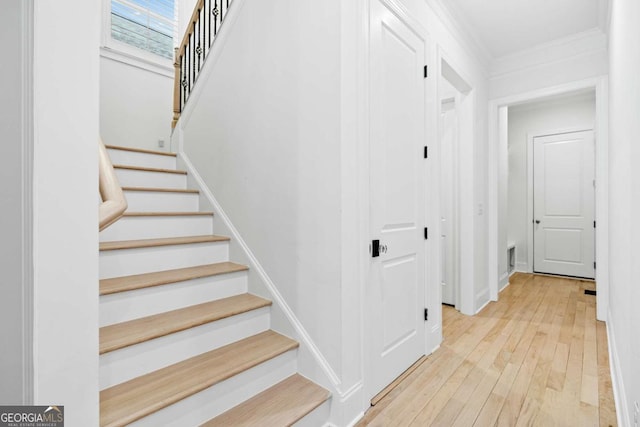 staircase with hardwood / wood-style flooring, crown molding, and baseboards