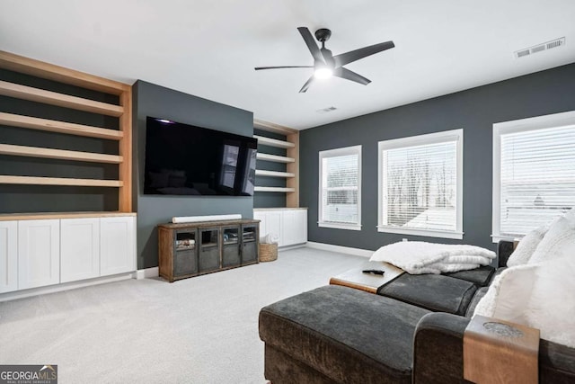 living area featuring carpet, built in shelves, a ceiling fan, and baseboards