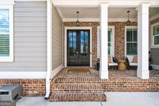property entrance featuring french doors, a porch, and brick siding