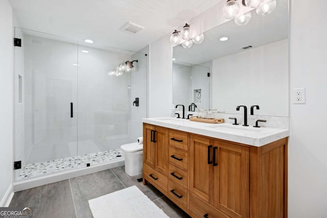 bathroom featuring a shower stall, double vanity, toilet, and recessed lighting