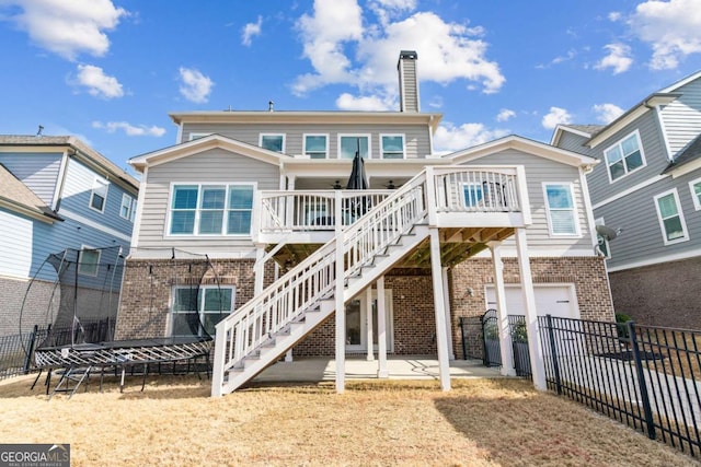 back of property featuring brick siding, fence, stairs, and a garage