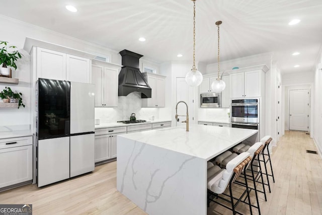 kitchen featuring appliances with stainless steel finishes, a sink, decorative backsplash, a breakfast bar, and custom exhaust hood