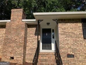 470 Ovara Ct, Stone Mountain, GA 30088 - view of exterior entry featuring crawl space, a chimney, and brick siding
