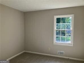 470 Ovara Ct, Stone Mountain, GA 30088 - spare room with dark colored carpet, visible vents, a healthy amount of sunlight, and baseboards