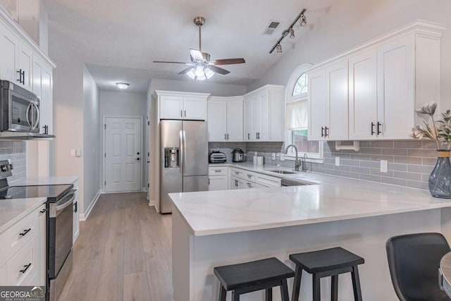 220 Chandler Ct, Sugar Hill, GA 30518 - kitchen with appliances with stainless steel finishes, a ceiling fan, white cabinetry, a sink, and a peninsula