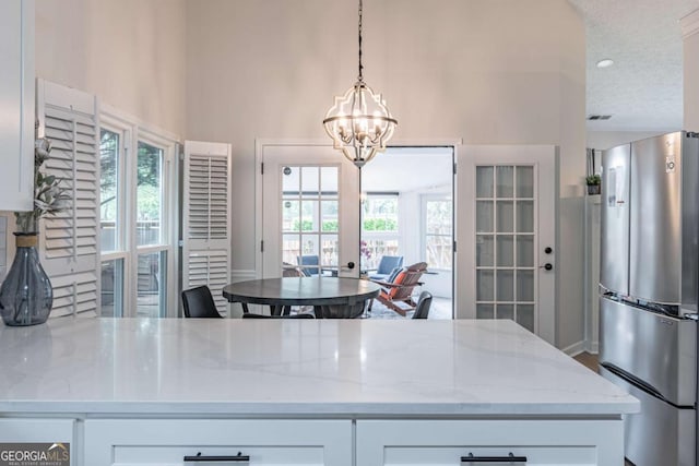 220 Chandler Ct, Sugar Hill, GA 30518 - kitchen featuring freestanding refrigerator, light stone countertops, a chandelier, white cabinetry, and a high ceiling