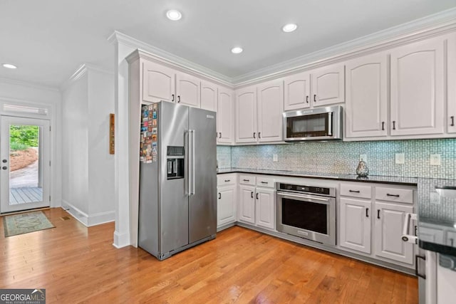 kitchen with ornamental molding, dark countertops, light wood finished floors, and stainless steel appliances